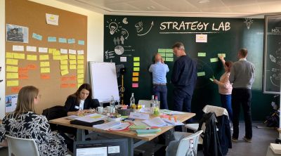 Andreas Klein und weitere Teilnehmer vor einer Strategie-Tafel mit Haftnotizen