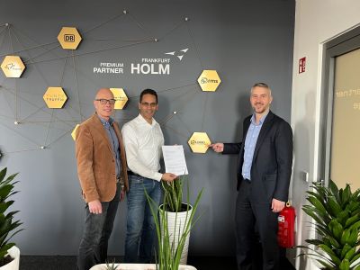 Huascar Rodriguez und Andreas Klein bei der Unterzeichnung einer Premium-Partnerschaft im HOLM Frankfurt vor einer Partnernetzwerk-Wand