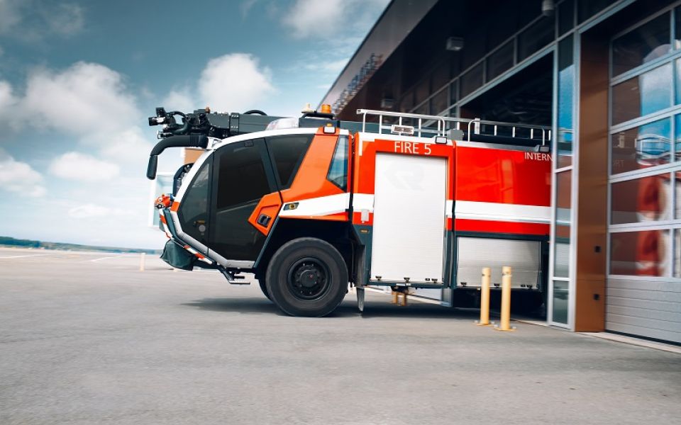 Rotes Flughafen-Feuerwehrfahrzeug auf dem Flughafengelände an einem Gebäude